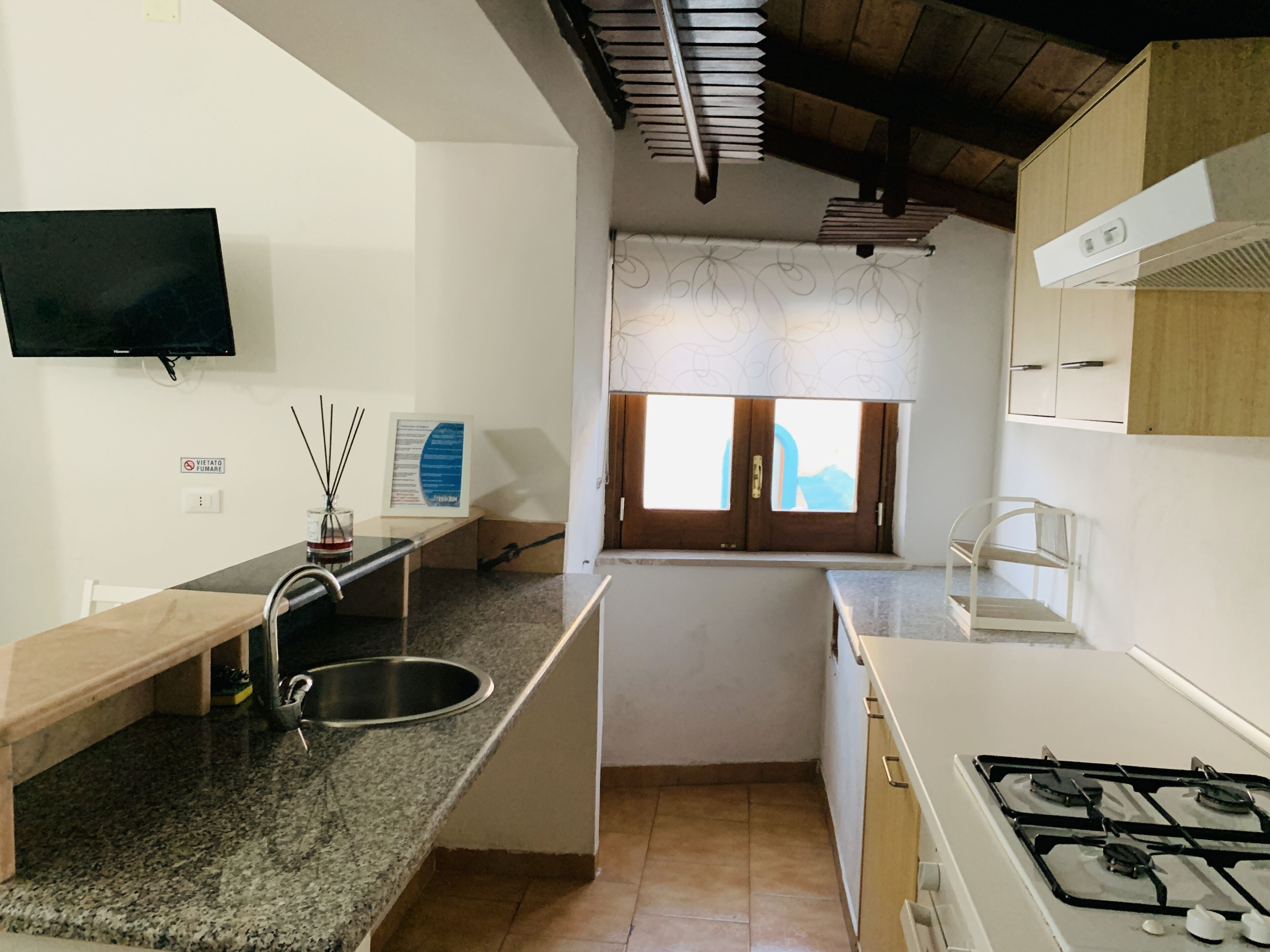 A kitchen with granite countertops, a stainless steel sink, a gas stove, and a window with a view.