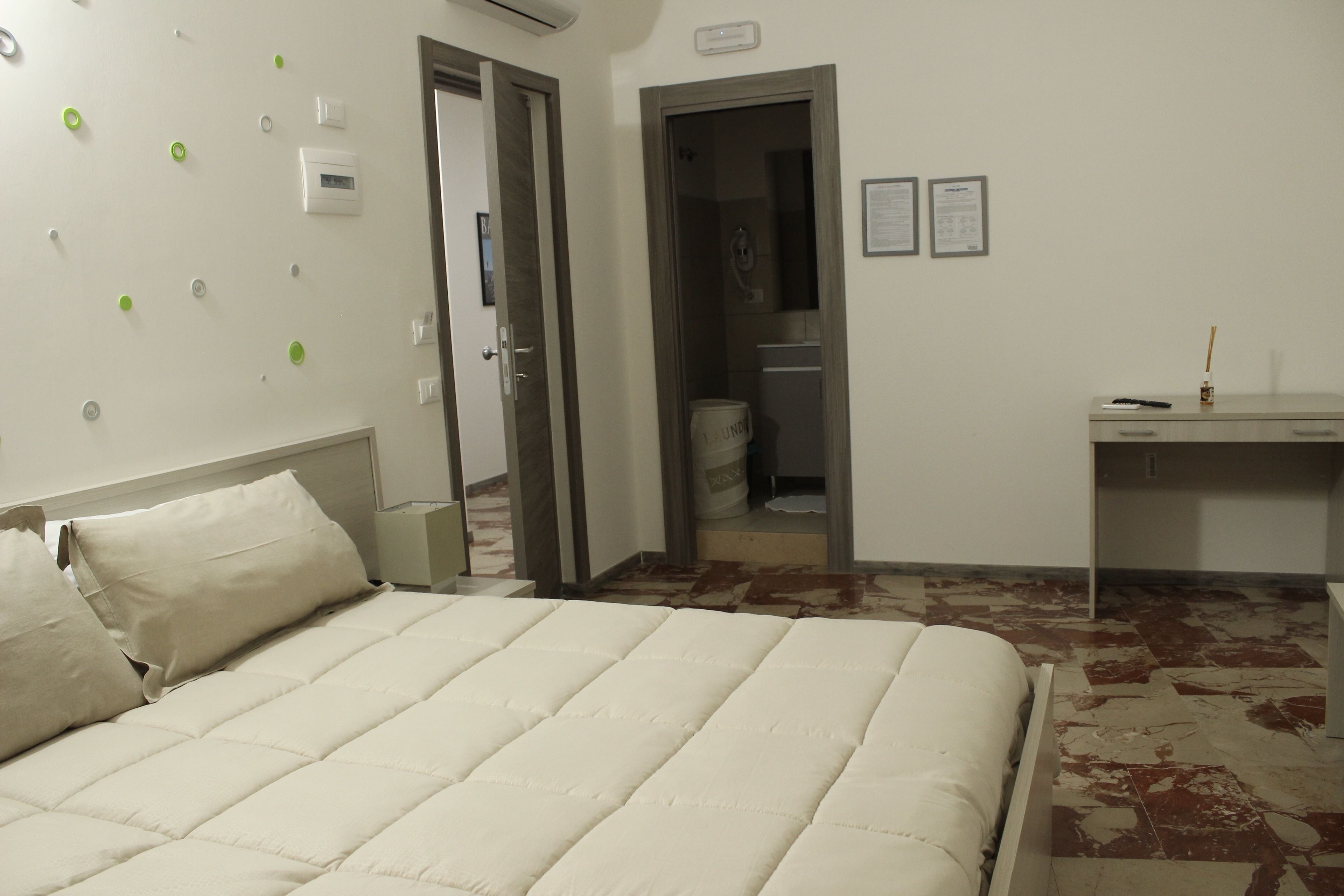 Habitación de hotel con cama, escritorio y baño visible a través de una puerta abierta.
