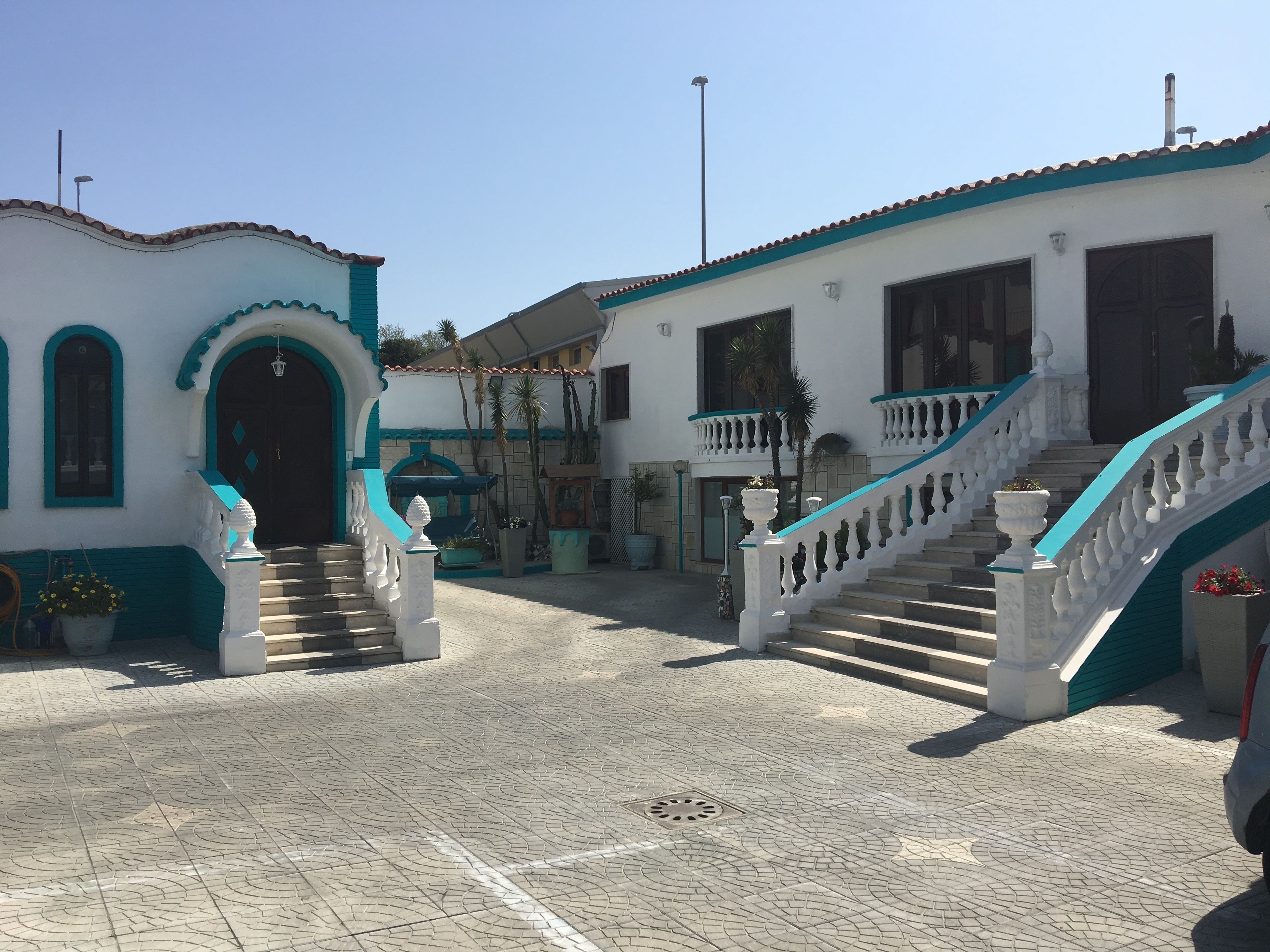 A building with a white facade, teal accents, and a staircase leading to the entrance.