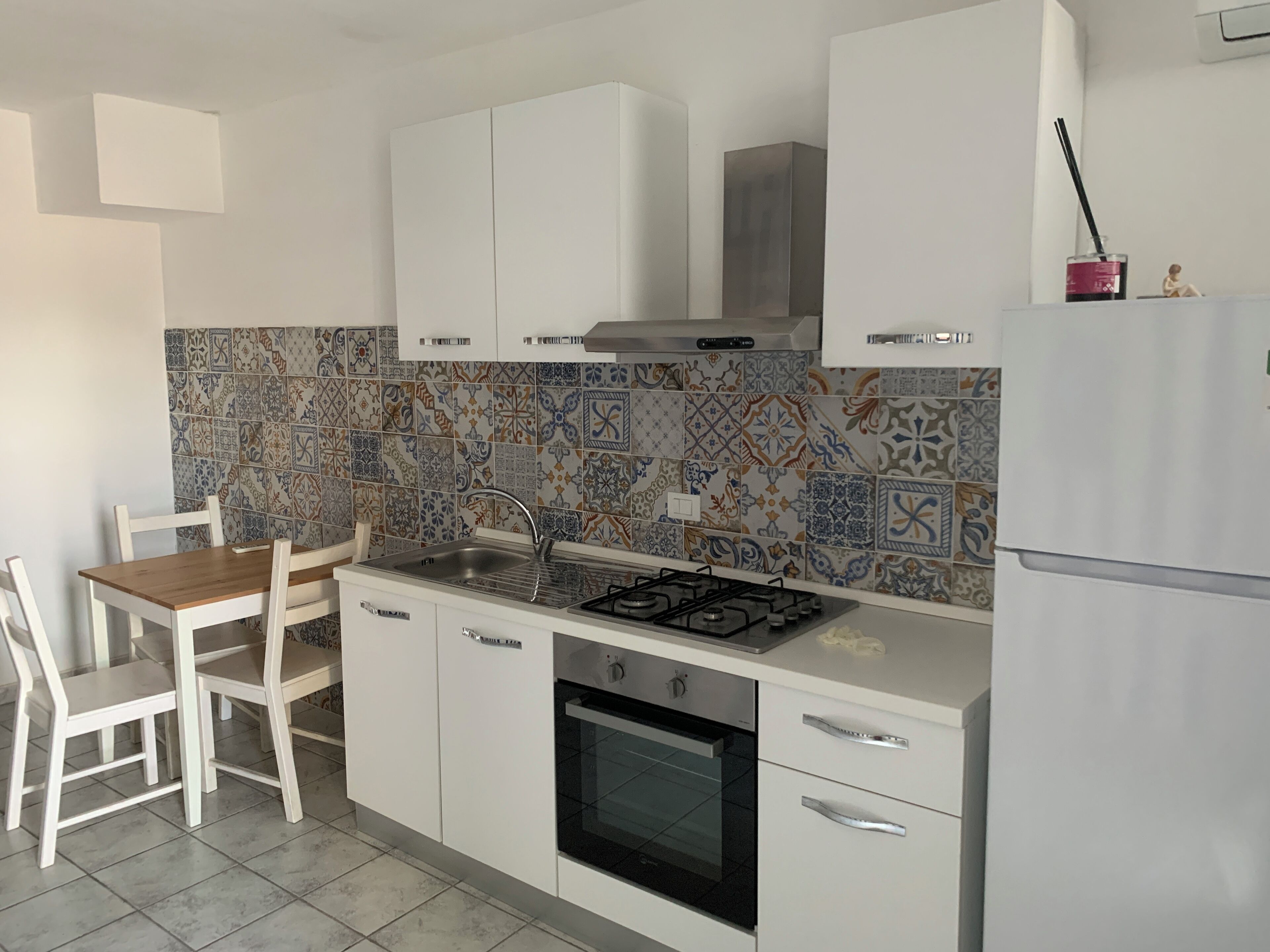 A modern kitchen with white cabinets, a gas stove, a built-in oven, and a tiled backsplash.