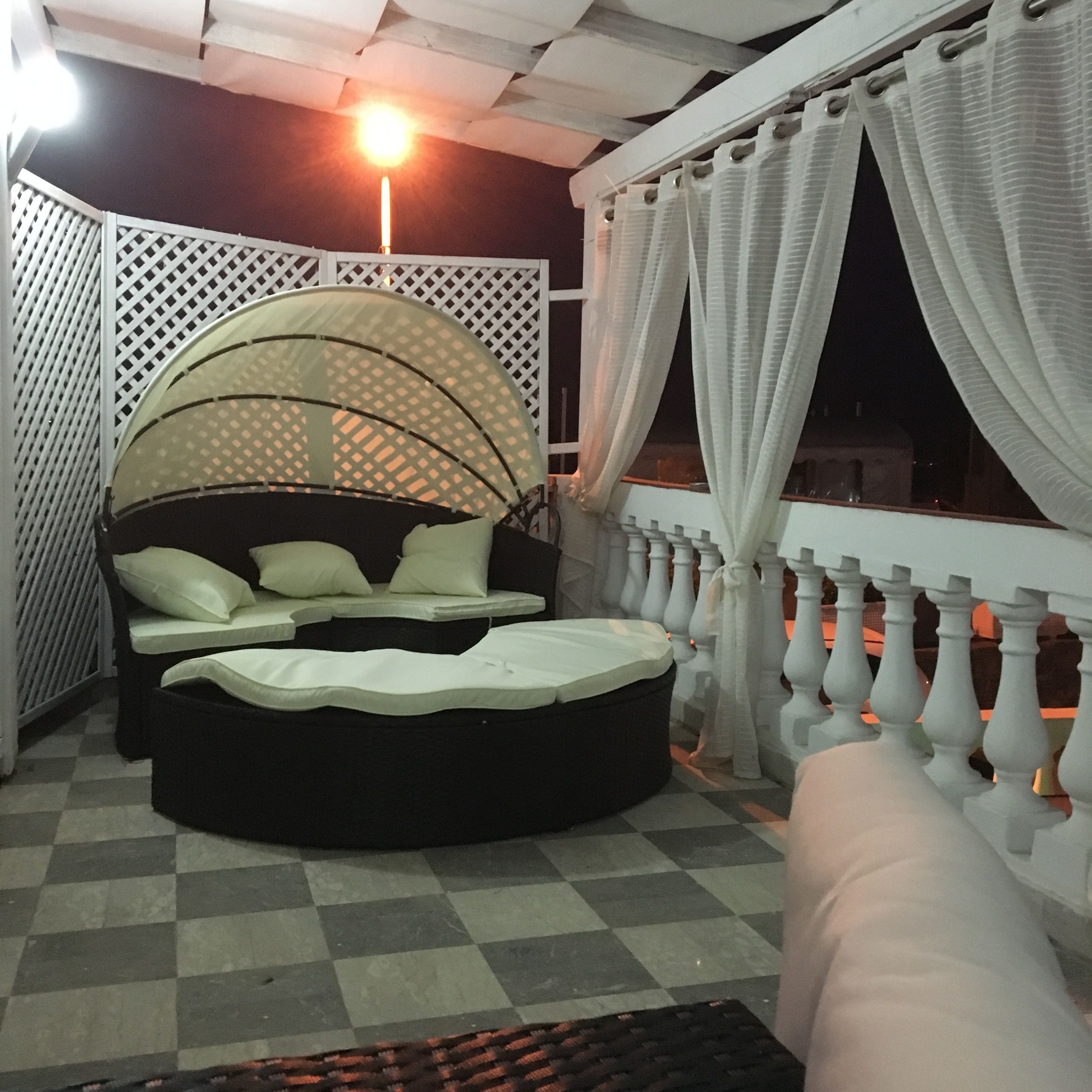 A circular bed with a canopy, a checkered floor, and a balcony with white curtains.