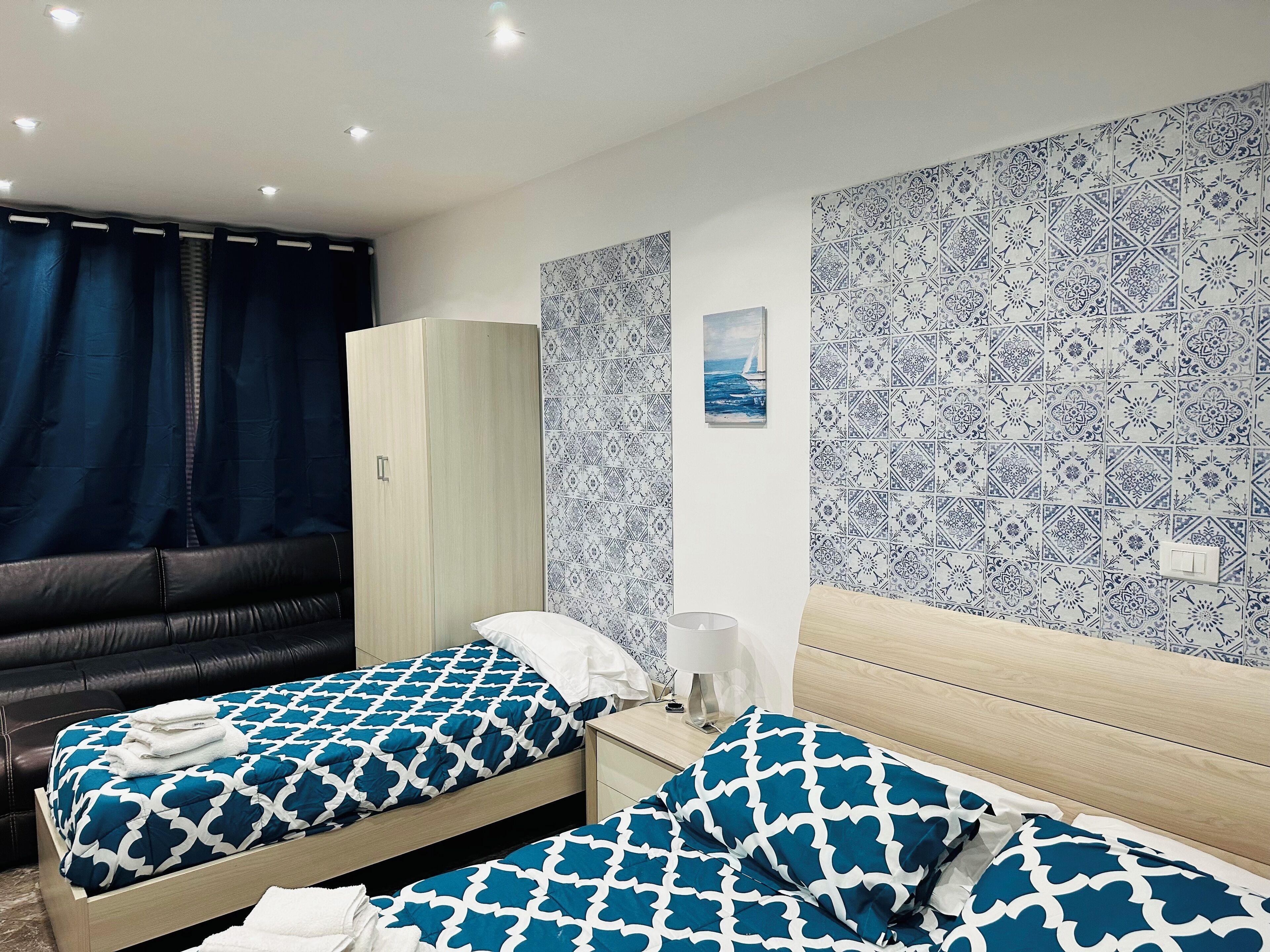 A hotel room with two beds, a wardrobe, a nightstand, and a painting on the wall.