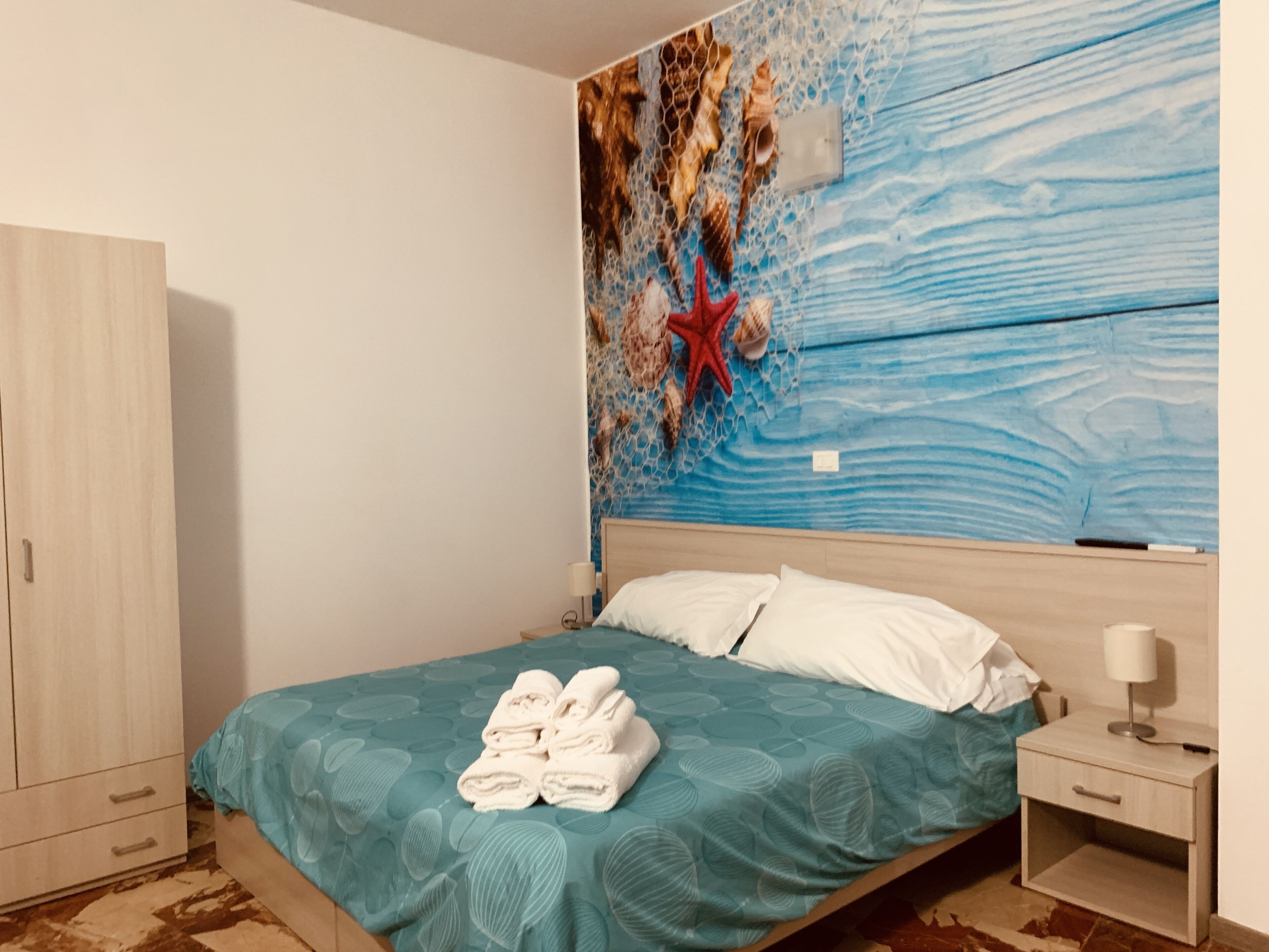 Une chambre à coucher comprenant un lit, une table de chevet, une armoire et une fresque murale.