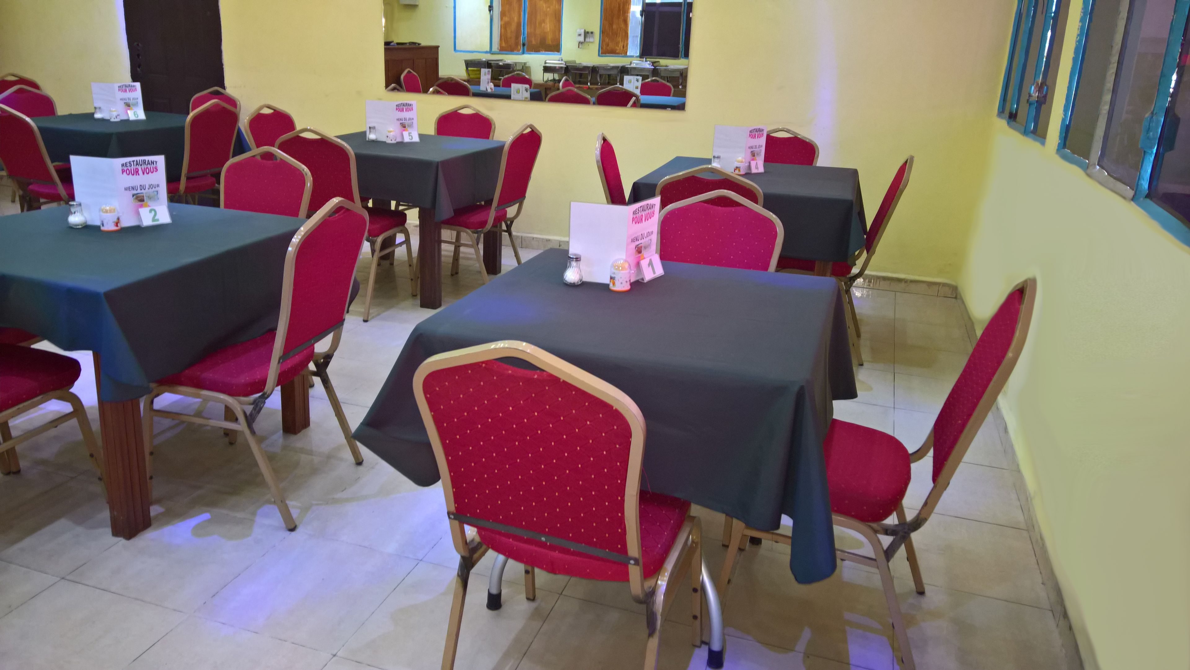 A dining area with tables and chairs, signs indicating a restaurant service, and a tiled floor.