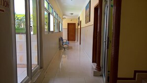 A hallway with a bench, a wooden door at the end, and a window on the left. - Hotel Pour Vous (Kinshasa)
