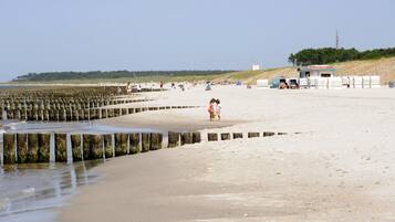 A beach with a wooden breakwater, a lifeguard tower, and a small building.