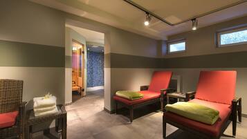 A spa room with wicker chairs, red cushions, and a tiled floor.