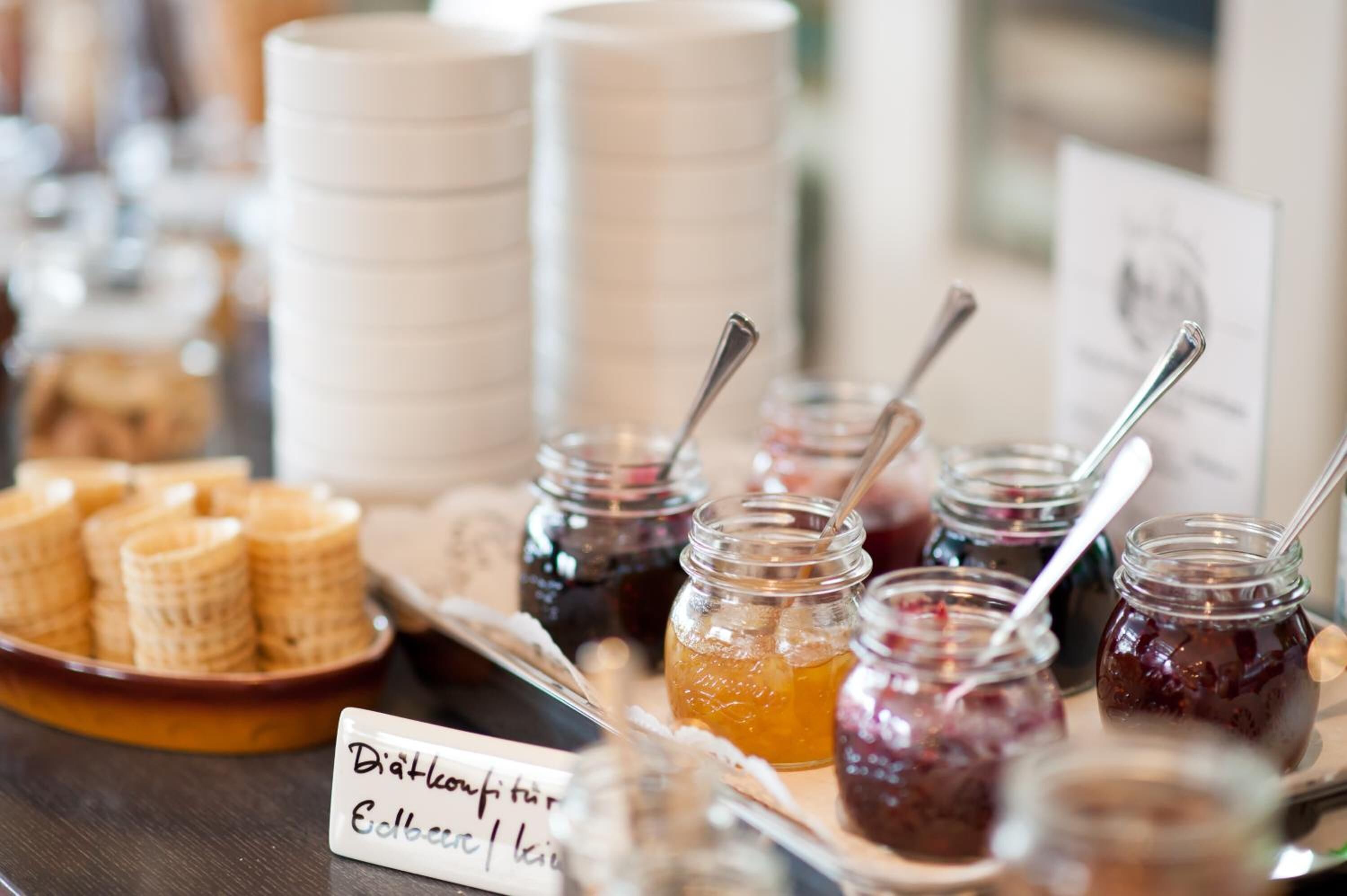 Un buffet proposant une variété de plats, notamment des gaufres et des pots de confitures.