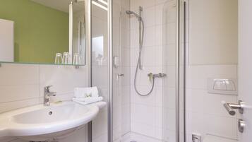 A modern bathroom with a glass-enclosed shower, a sink, and a toilet.