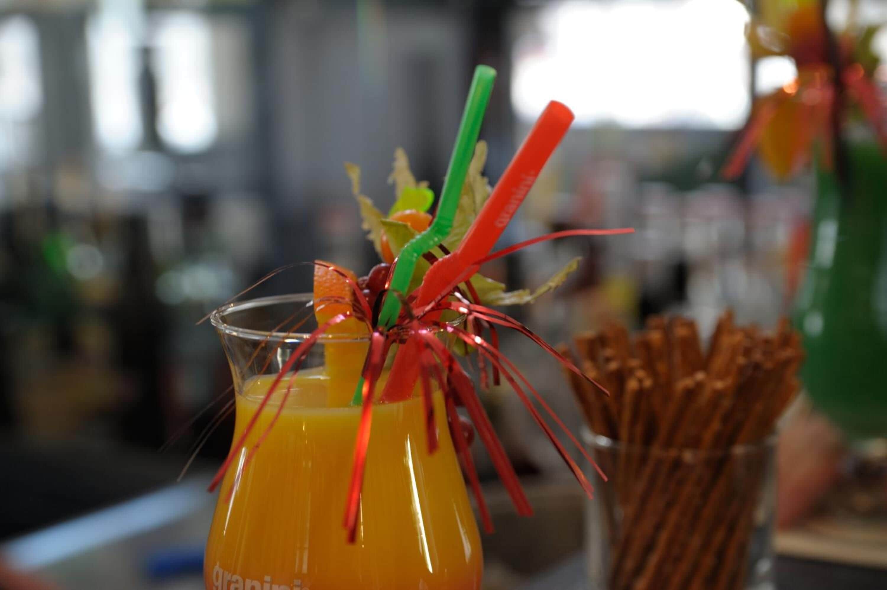 Un verre contenant une boisson jaune, agrémenté de pailles colorées et d’un élément décoratif.