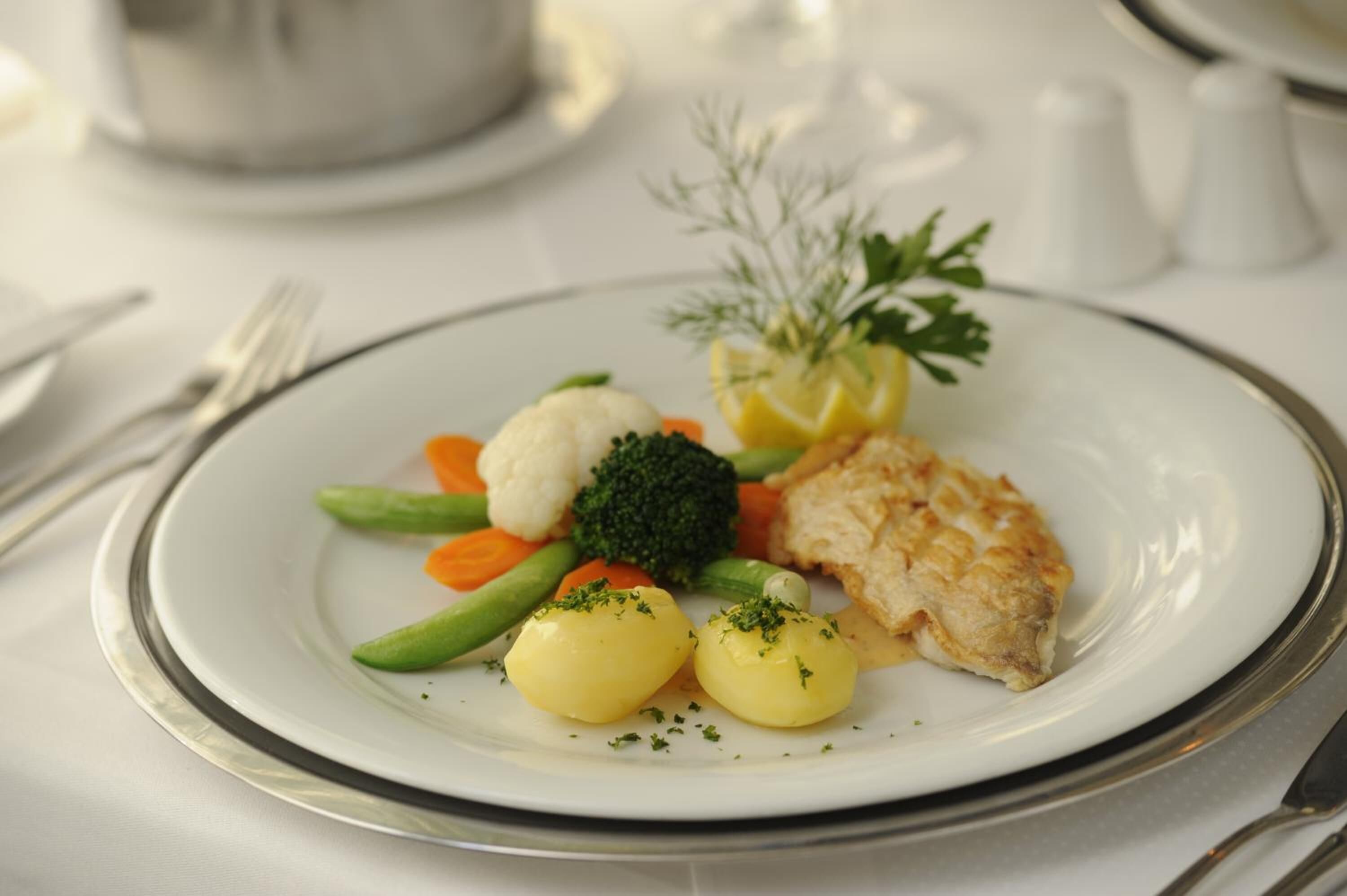 En tallrik med mat, bestående av grönsaker och en bit fisk.
