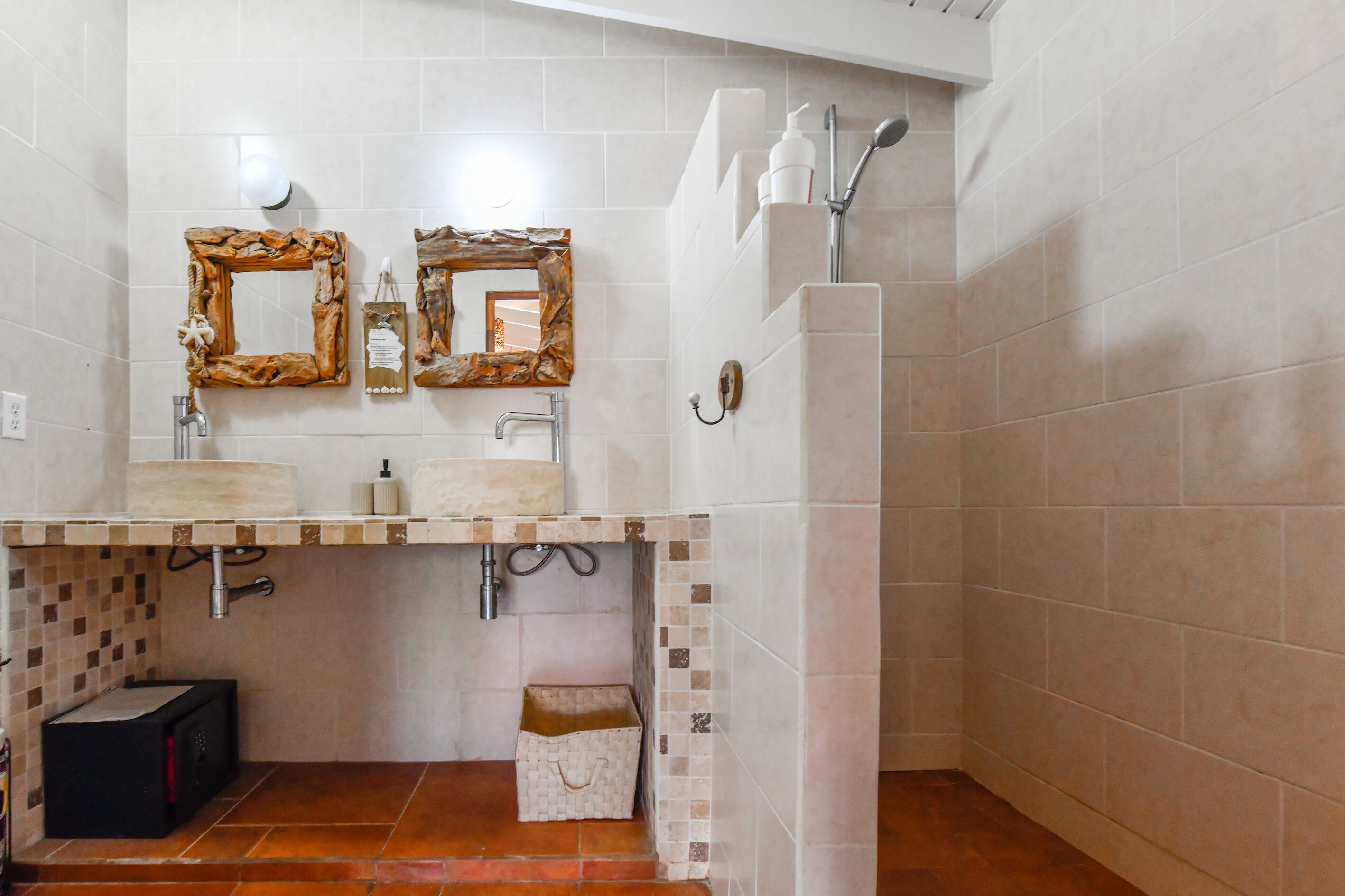 Ein Badezimmer mit zwei Waschbecken, einer Dusche und gefliestem Boden.