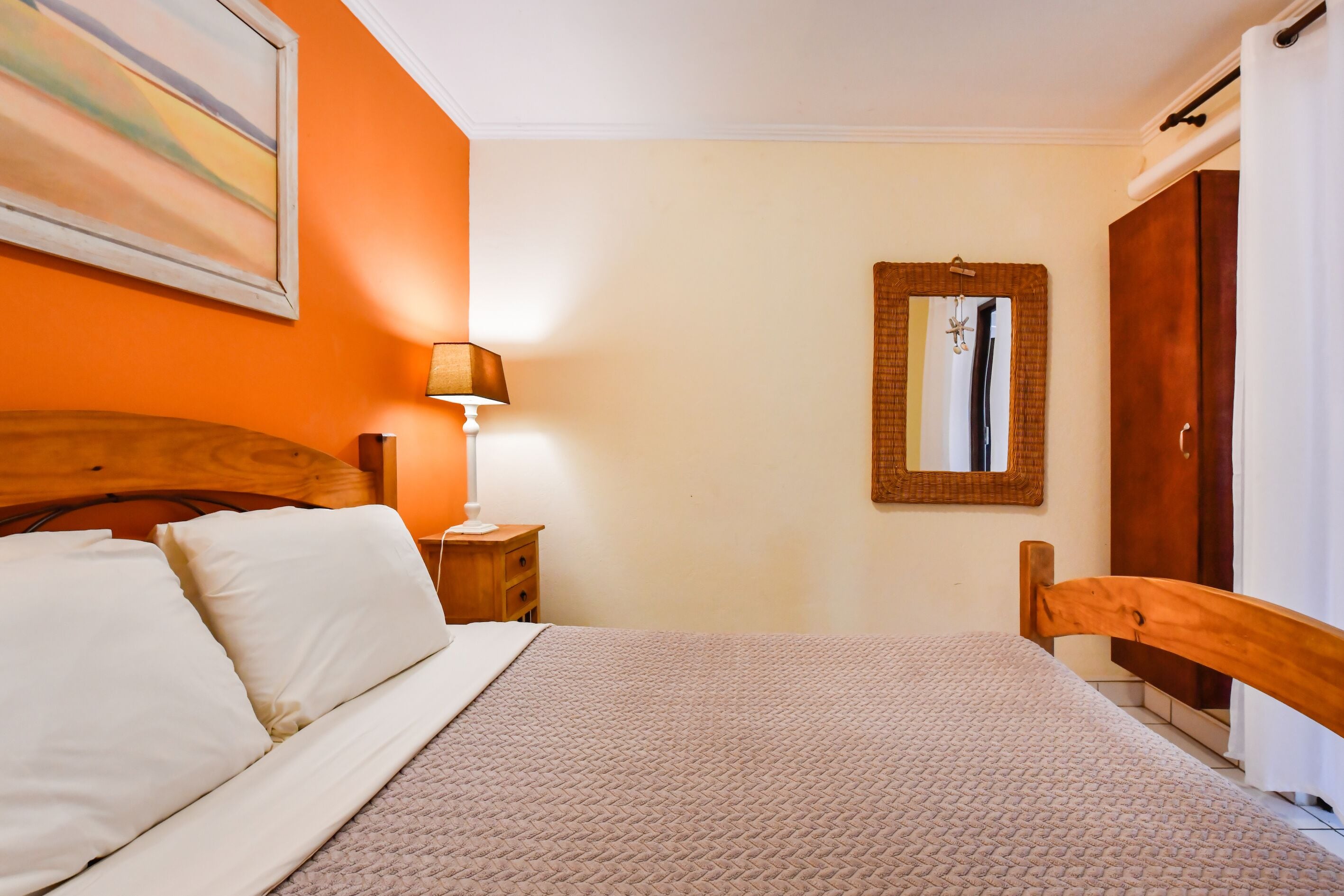 Un dormitorio con cama, mesita de noche, lámpara, espejo y armario.