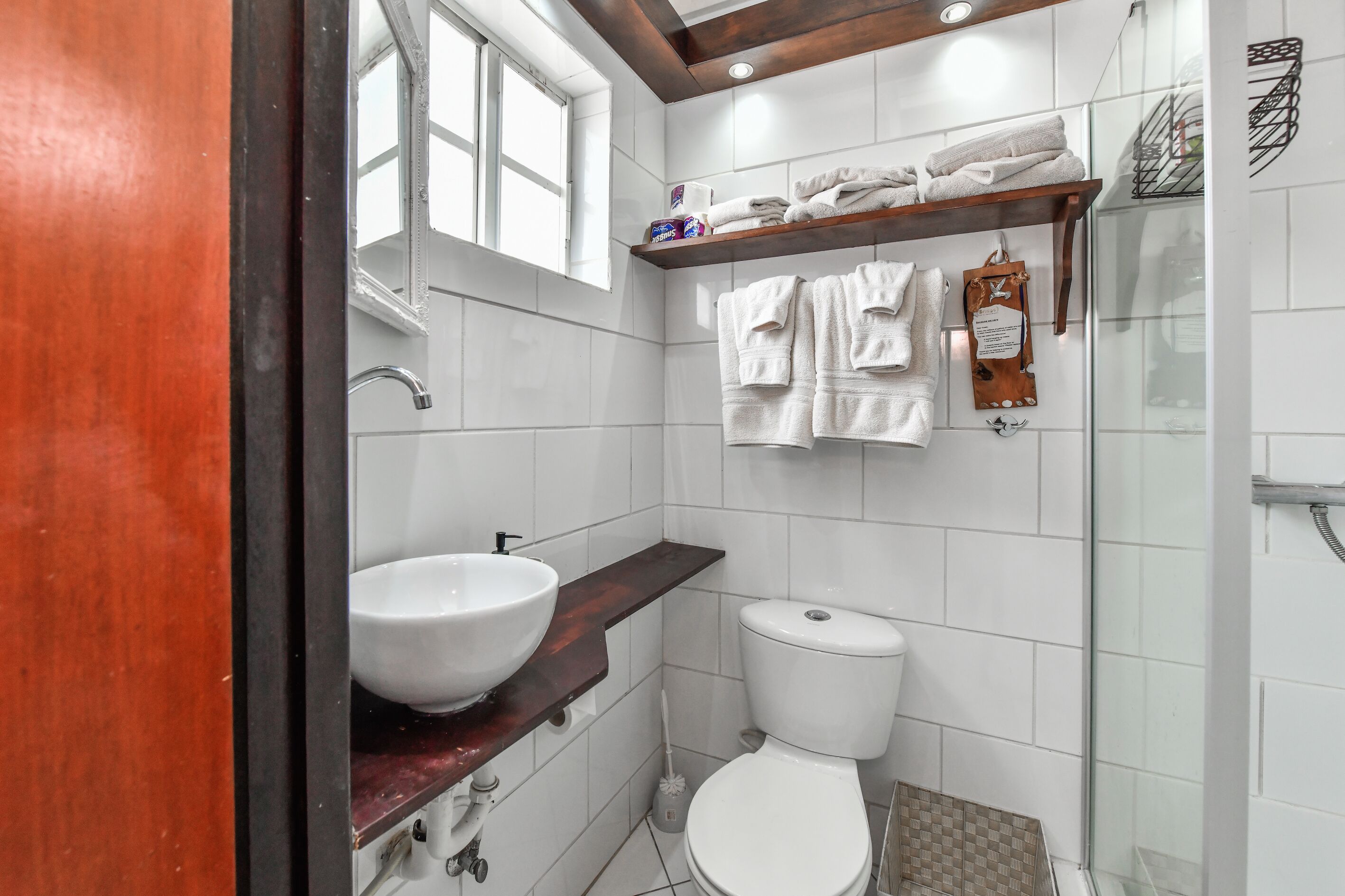 Un baño moderno con un lavabo grande de color blanco, un inodoro y una cabina de ducha con mampara de vidrio.