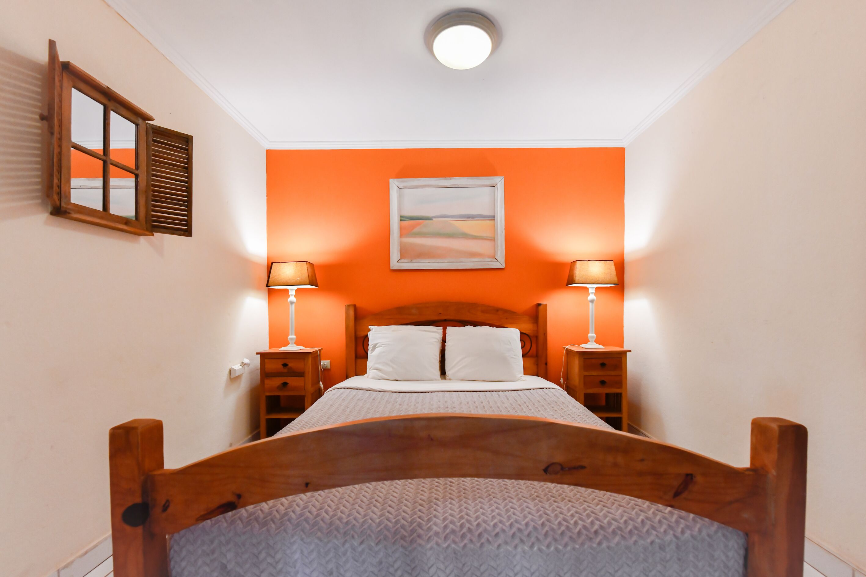 Una camera da letto con un letto di legno, due comodini e un quadro appeso al muro.