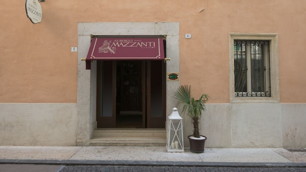Fachada de un edificio con un toldo color burdeos que muestra el nombre 'Albergo Mazzanti'.