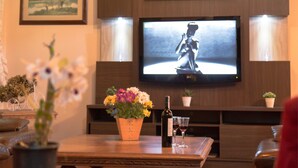 Una sala de estar con una mesa de centro de madera, un televisor en la pared y una planta en maceta.