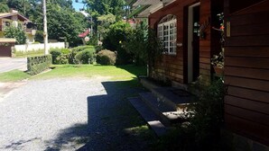 Una casa de madera con entrada de grava, rodeada de follaje y árboles.