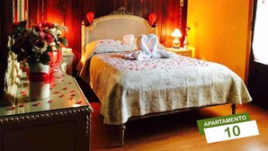 Un dormitorio acogedor con techo de madera, una cama con cubrecama blanco y un florero sobre una mesita de noche.