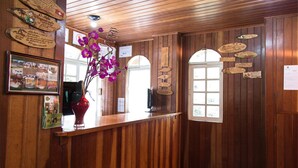Un mostrador de recepción de madera con un florero de flores moradas, cuadros enmarcados y placas de madera en la pared.