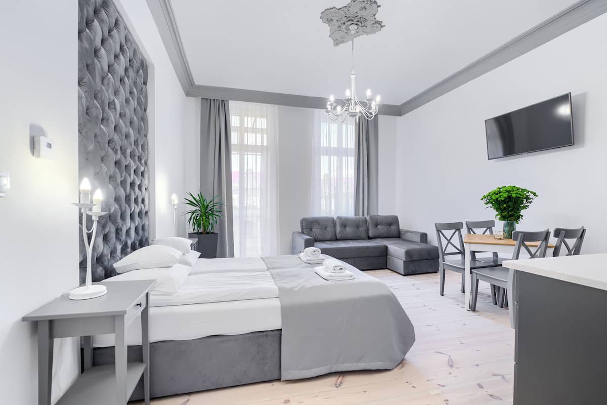 Una habitación de hotel moderna con cama, zona de estar, mesa de comedor y televisor.