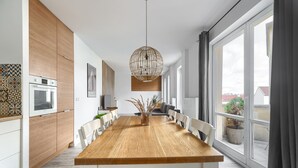Una cocina moderna con una mesa de comedor de madera, sillas blancas y una lámpara colgante.