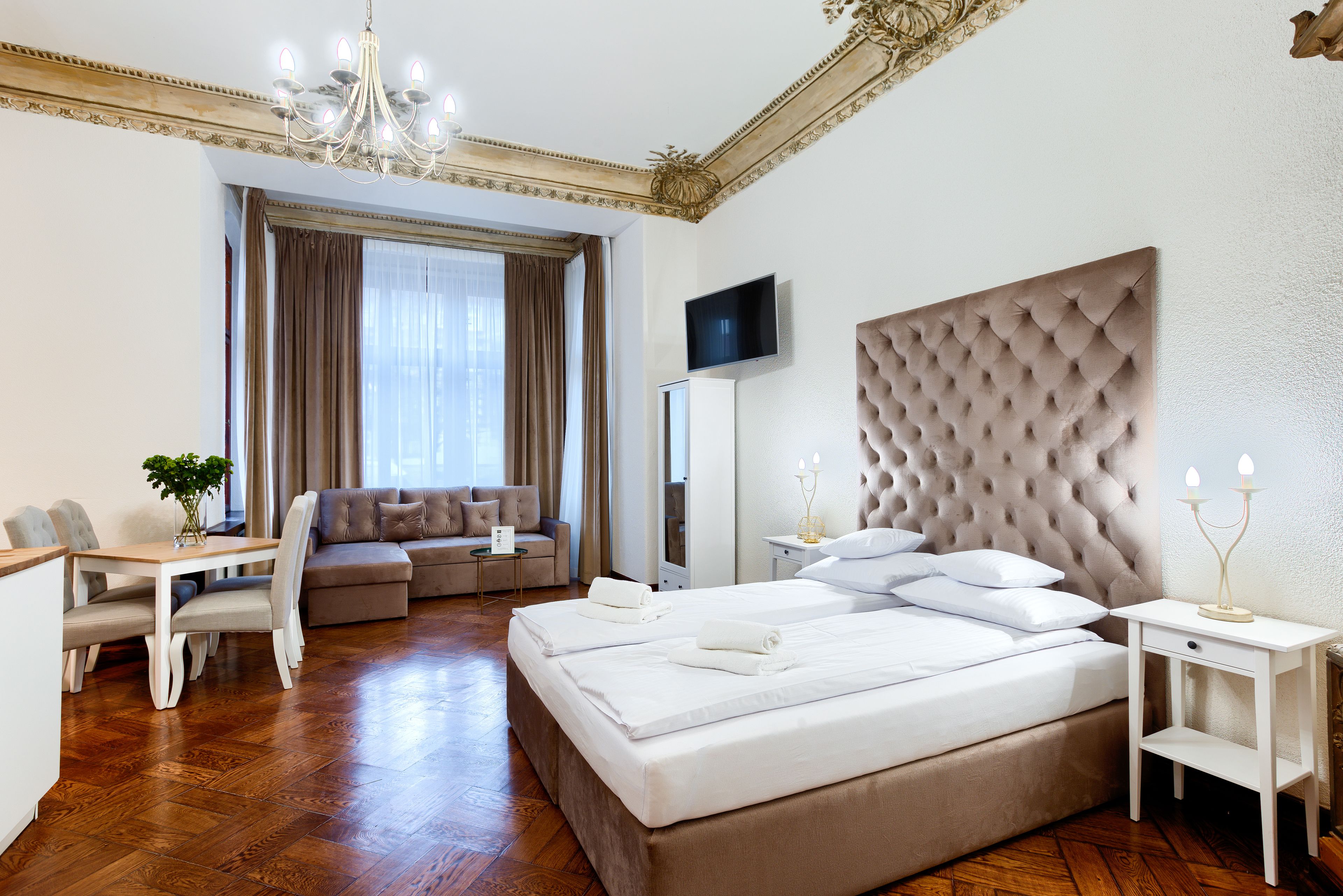 Quarto de hotel com uma cama grande, um sofá, uma mesa de jantar e uma televisão.