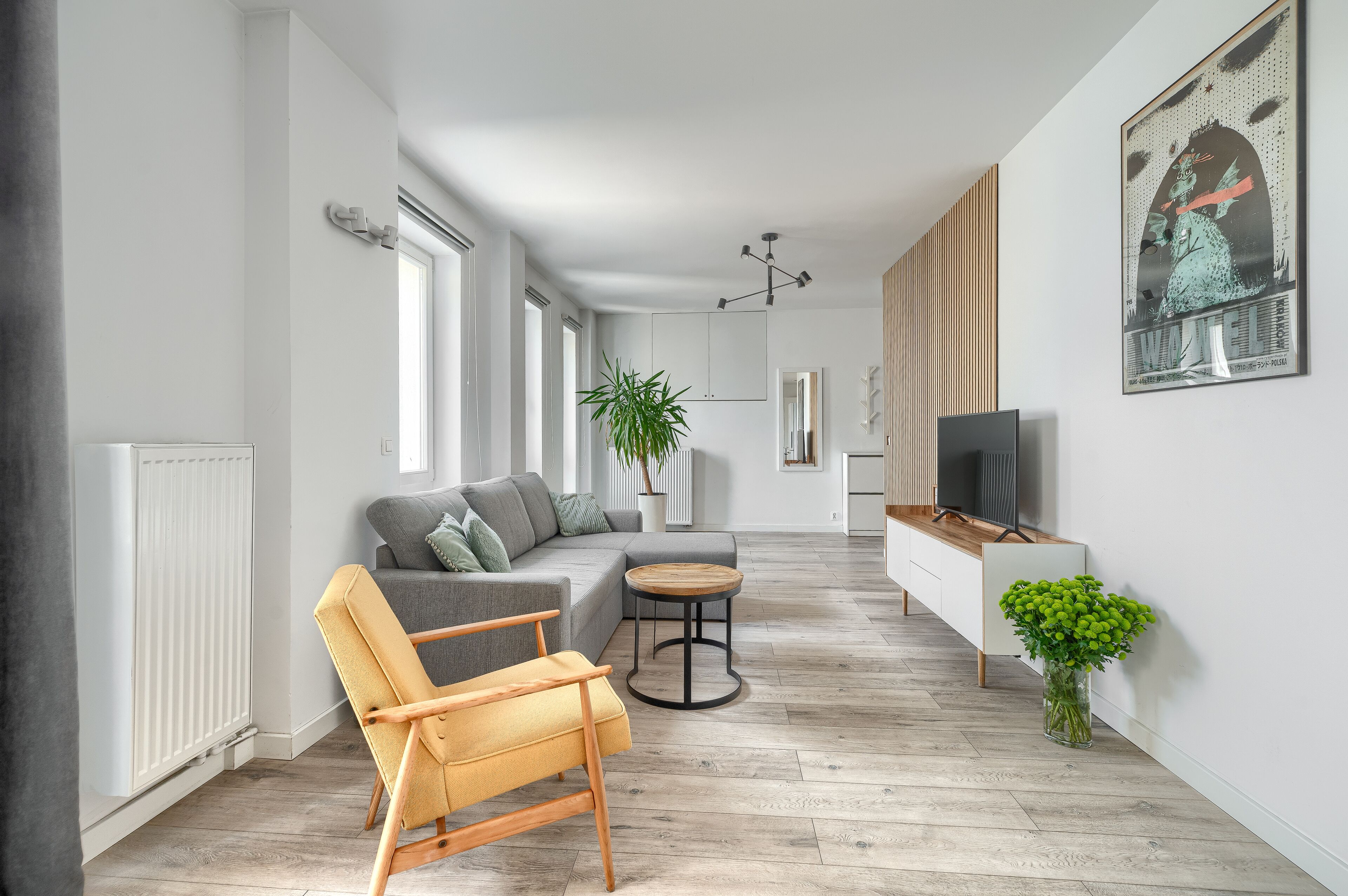 A modern living room with a sofa, armchair, coffee table, and a TV on a wooden cabinet.