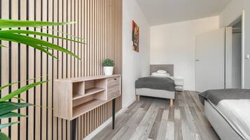 A modern bedroom with a wooden slat wall, a bed, a bedside table, and a small potted plant.