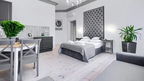 Un dormitorio moderno con cama, mesitas de noche, un escritorio y una zona de comedor.