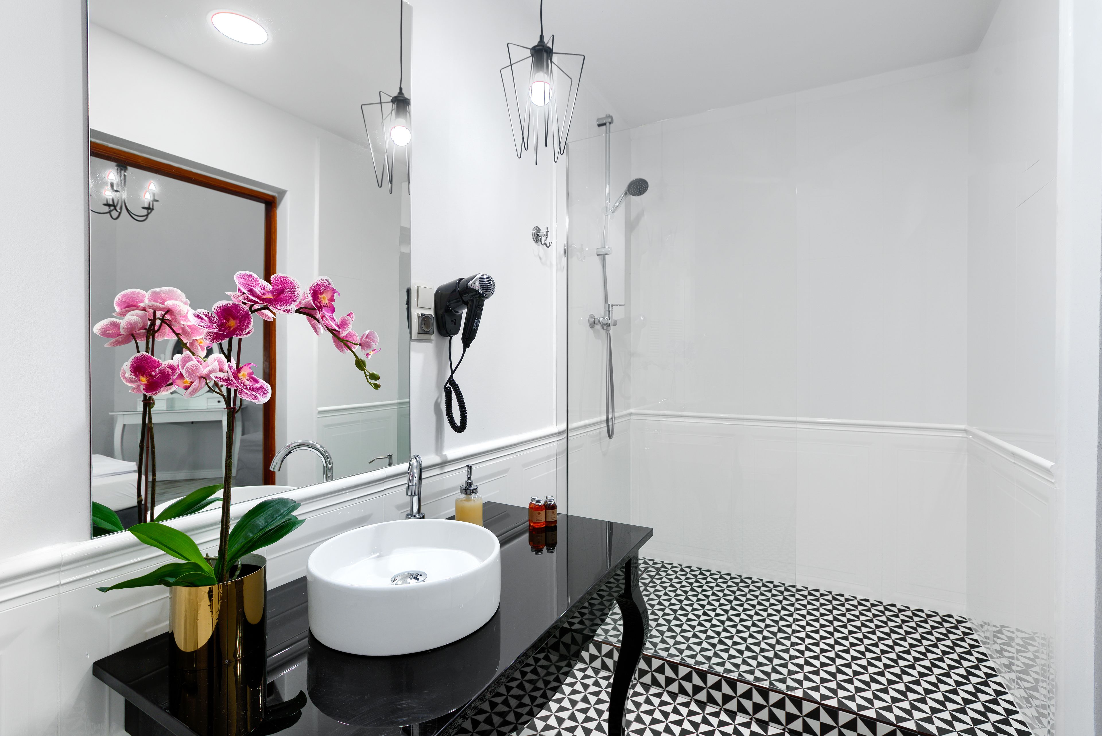 A modern bathroom with a white sink, black countertop, and patterned floor tiles.