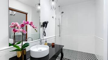 Une salle de bain moderne avec un lavabo blanc, un plan de toilette noir et des carreaux de sol à motifs.