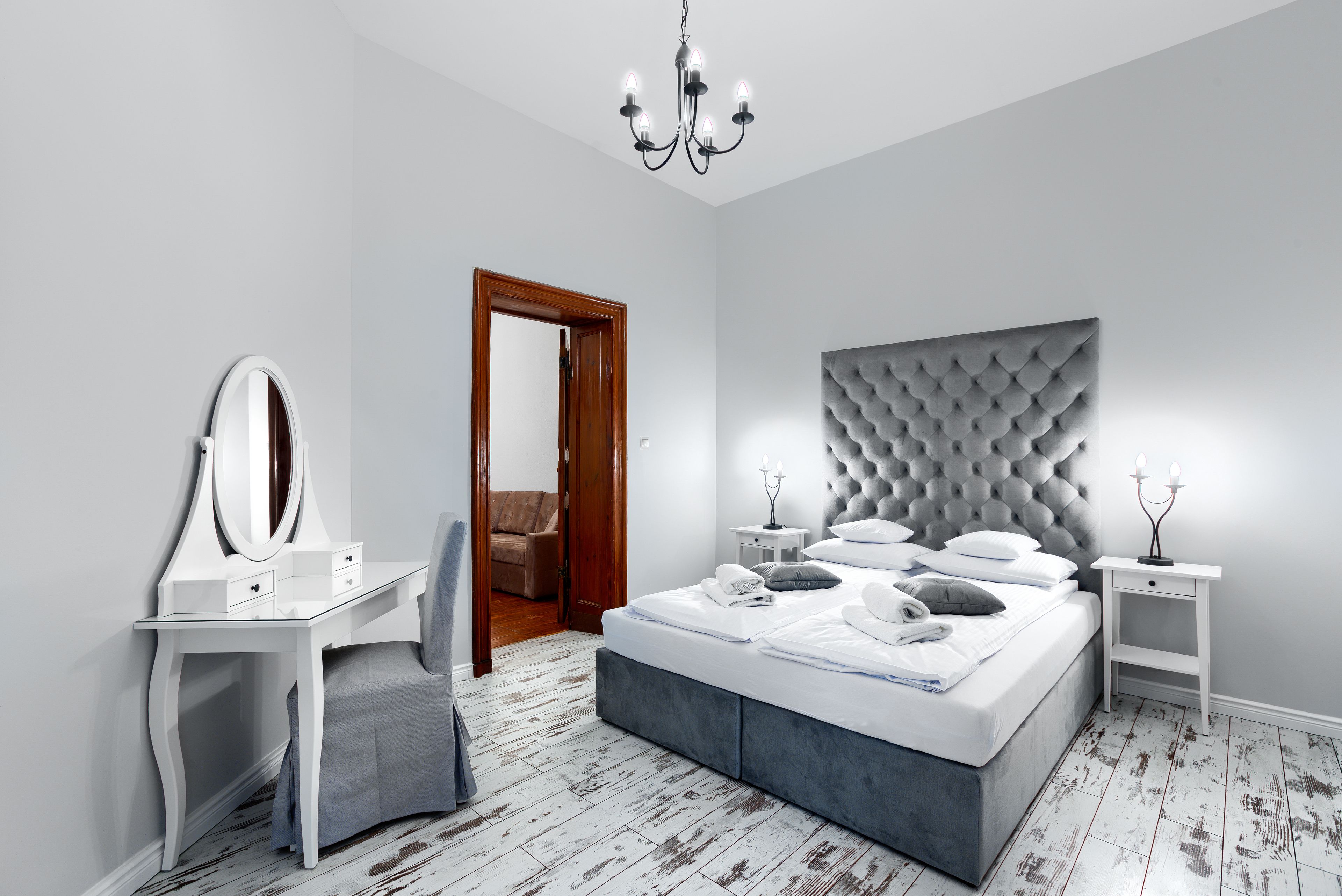 Una camera da letto con un letto, una toeletta con specchio, un comodino e un lampadario.