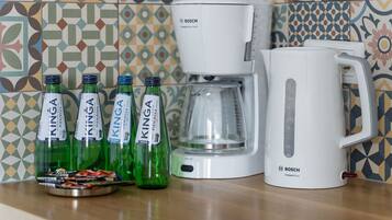 Uma cozinha com uma cafeteira e chaleira Bosch, e quatro garrafas verdes de cerveja King em uma bandeja.