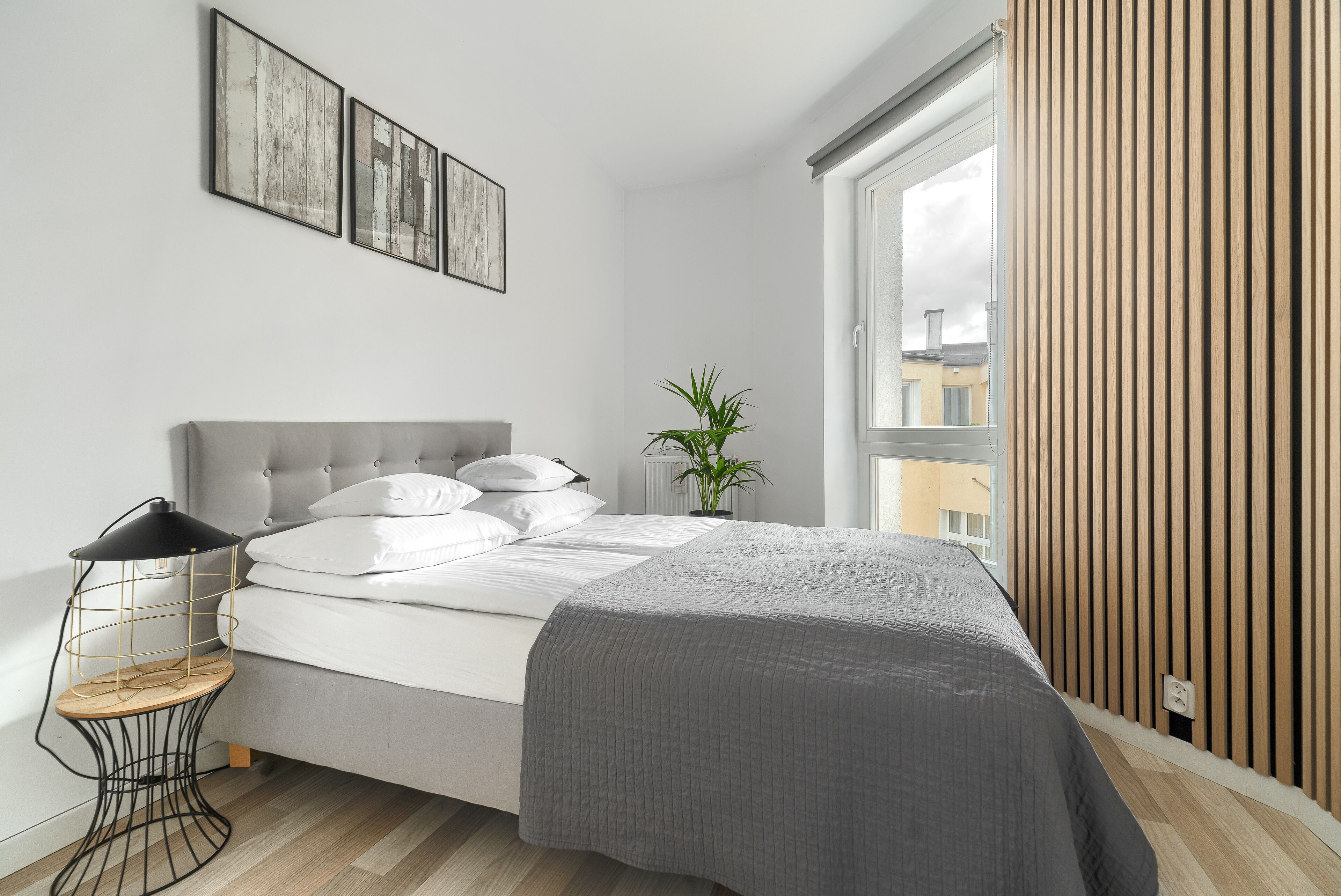Ein modernes Schlafzimmer mit Bett, Nachttisch und einem Fenster mit Holzjalousien.