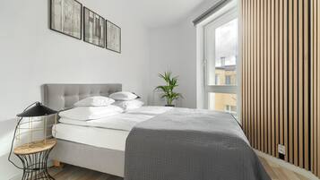 Ein modernes Schlafzimmer mit Bett, Nachttisch und einem Fenster mit Holzjalousien.