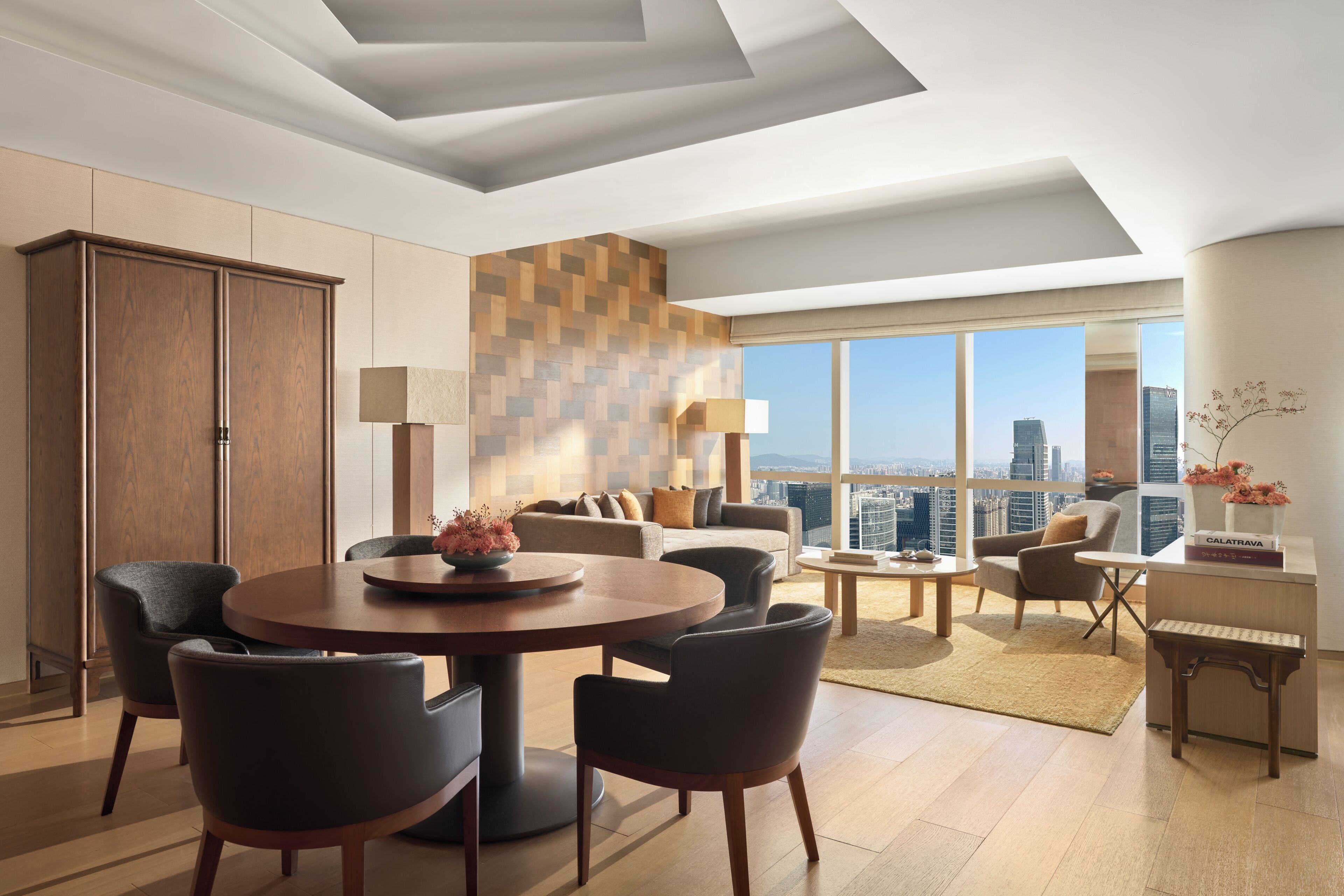A modern living room with a dining area, large windows, and a city view.
