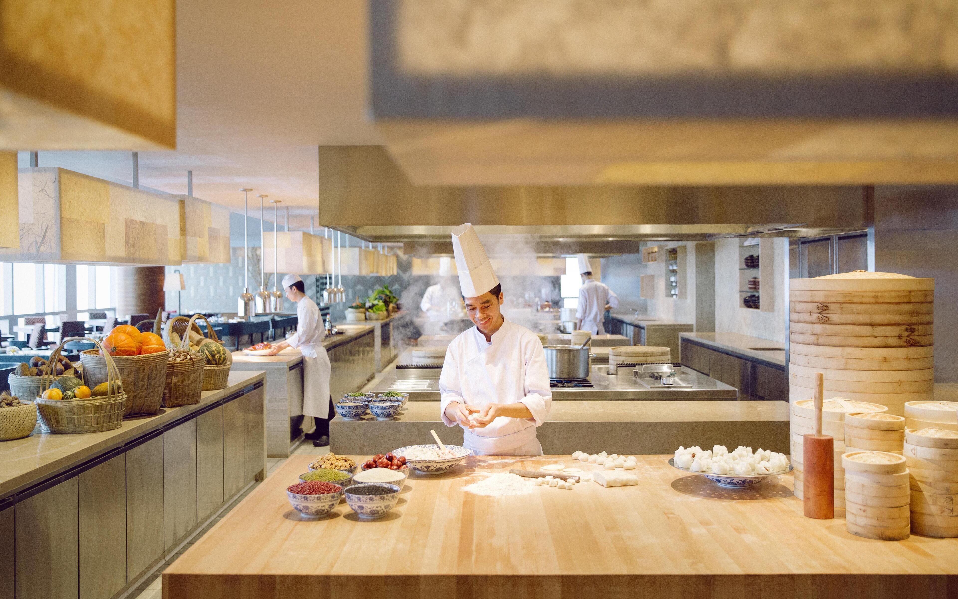 A chef preparing food in a modern kitchen with various ingredients and cooking utensils.