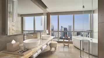 A modern bathroom with a large window, a bathtub, and two sinks.