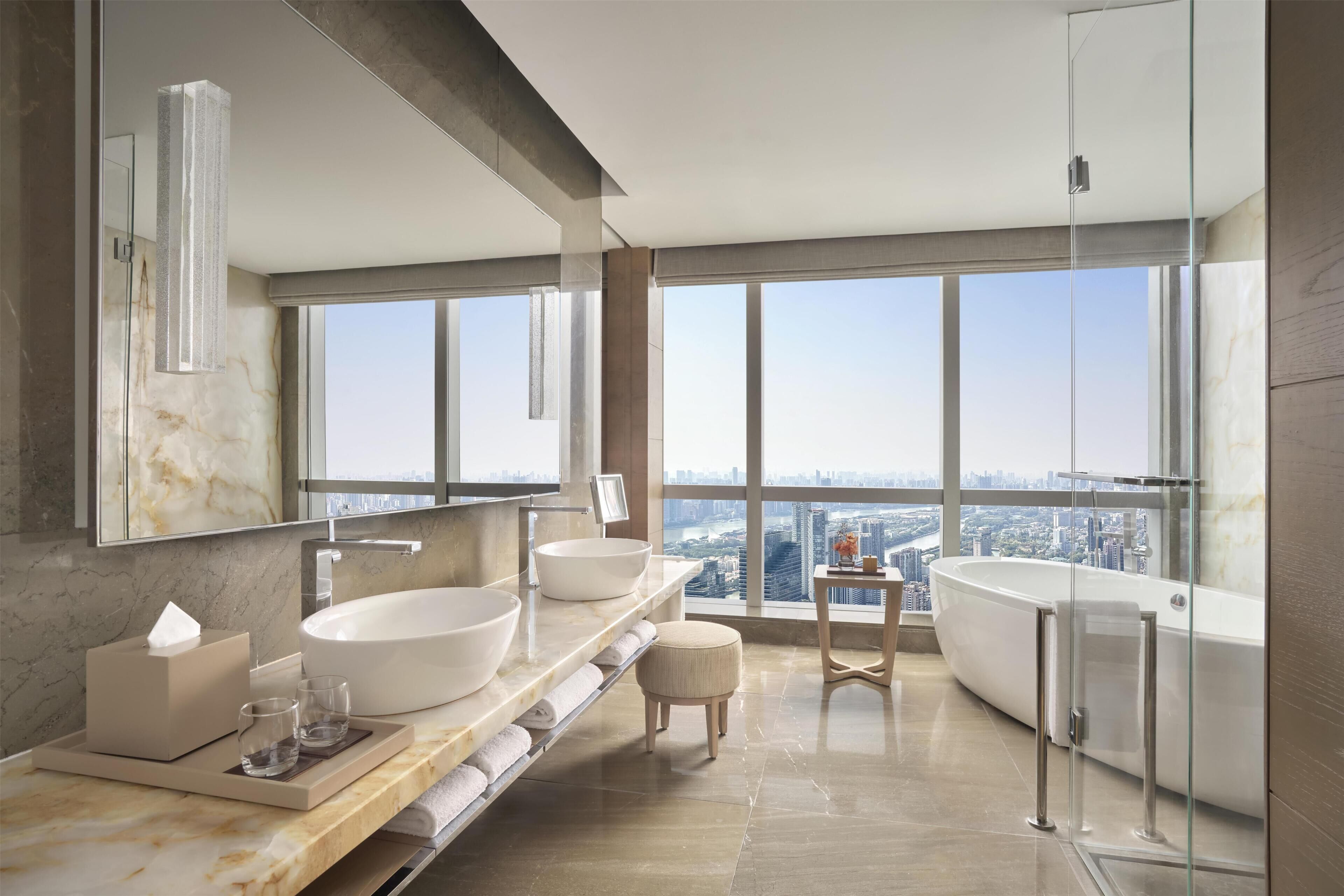 Un baño moderno con un ventanal grande, una bañera y un tocador con dos lavamanos.