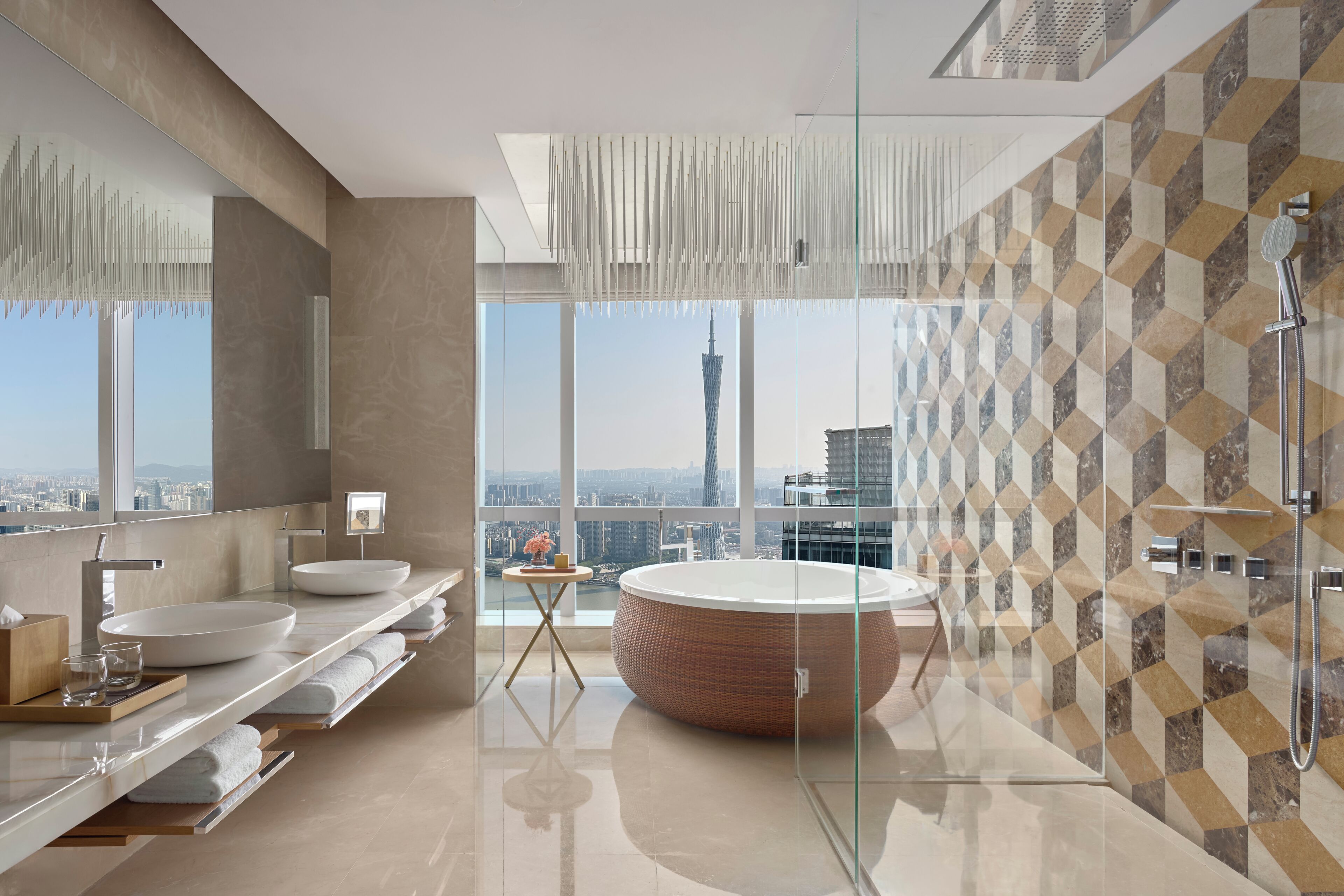 A modern bathroom with a large bathtub, a round mirror, and a city view.