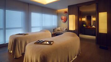 Relax in a serene space with two comfortable beds, a bathroom with a mirror, and a table with a lamp.