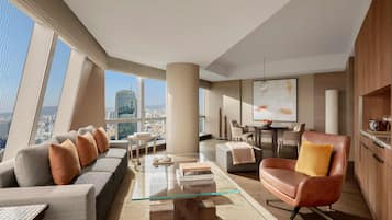 A modern living room with a glass coffee table, sofas, and a leather armchair.