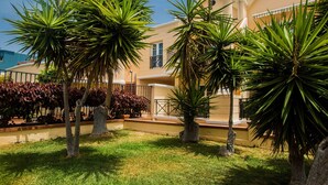 A residential building with a well-maintained lawn and several palm trees. - Yucca Park Aparthotel (Adeje)