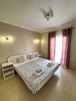 A bedroom with a bed, bedside tables, a ceiling fan, and curtains. - Yucca Park Aparthotel (Adeje)