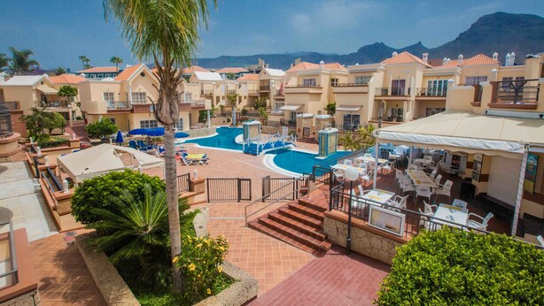 A resort with a swimming pool, outdoor seating, and a view of mountains. - Yucca Park Aparthotel (Adeje)