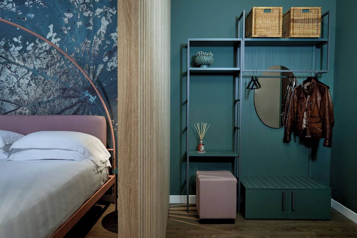 A bedroom with a bed, a wardrobe, and a mirror.