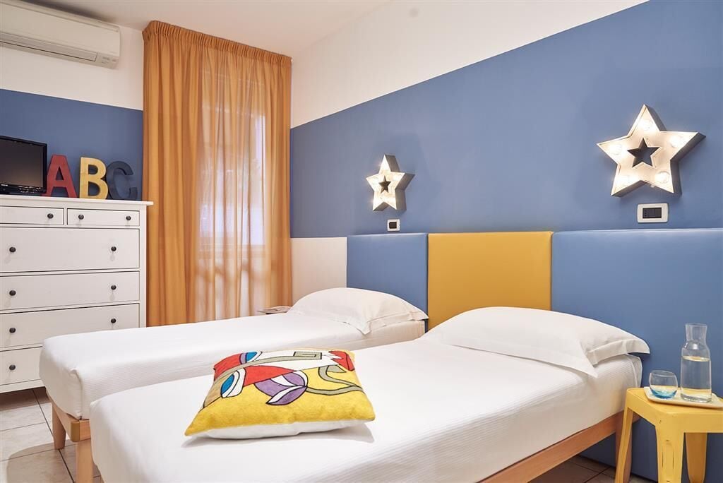 A hotel room with two beds, a dresser, and star-shaped wall decorations.