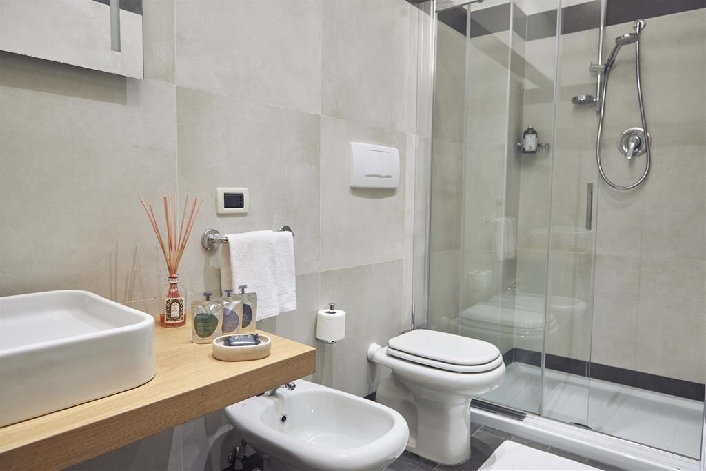 Un baño moderno con ducha acristalada, lavamanos blanco y bidé.