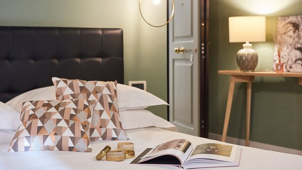 A neatly made bed with patterned pillows, a bedside table with a lamp, and a framed picture on the wall. - Residence Leopoldo (Florence)